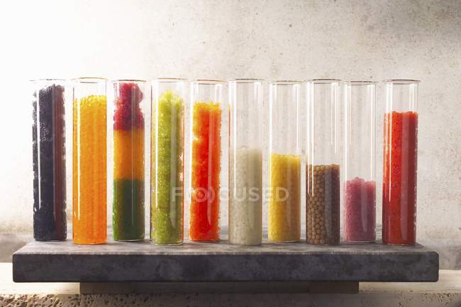 Selección de huevas de pescado de diferentes colores en recipientes de vidrio en una fila - foto de stock