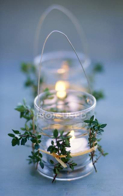 Vista de primer plano de candelabros encendidos en vasos con hierbas atadas - foto de stock