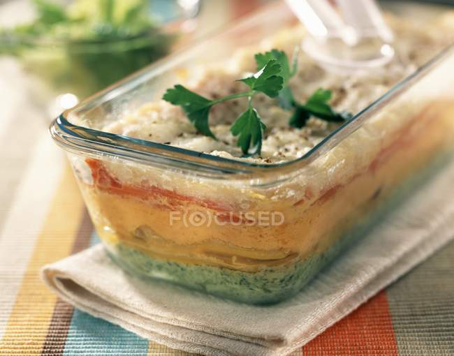 Five coloured vegetable flan terrine in glass dish over towel — Stock Photo