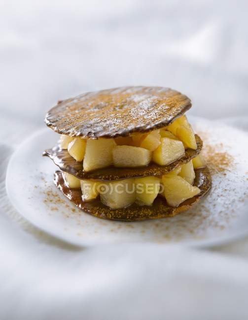 Chocolate tuile biscuit and pear Mille-feuille  on white plate — Stock Photo