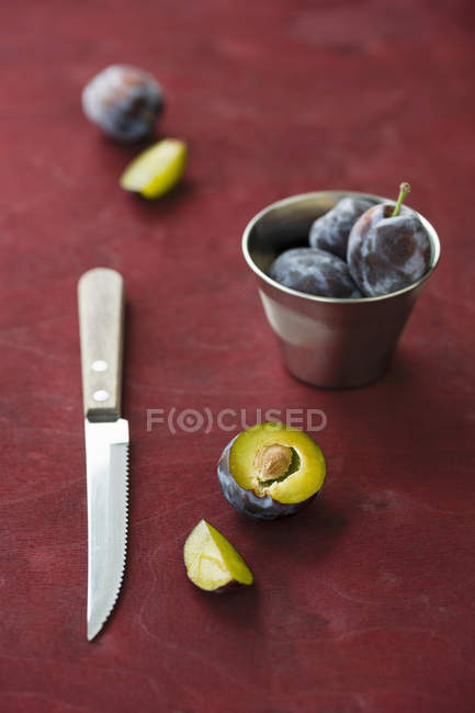 Damsons with metal cup and knife — Stock Photo
