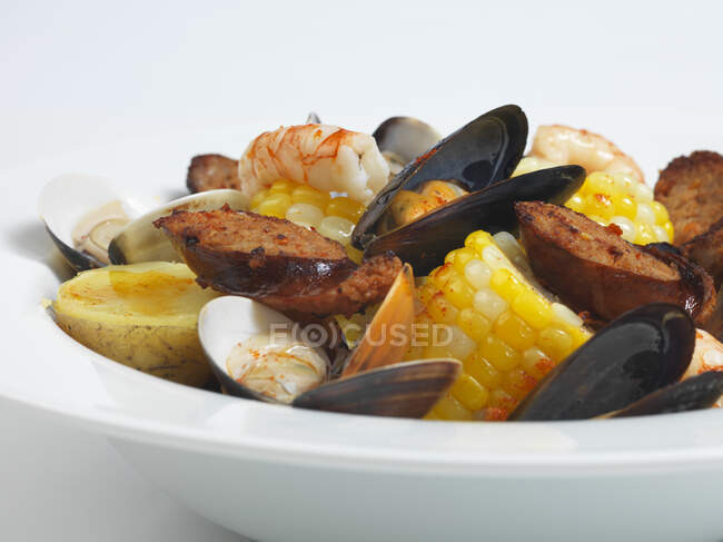 Estofado de mariscos con salchichas, patatas y maíz - foto de stock