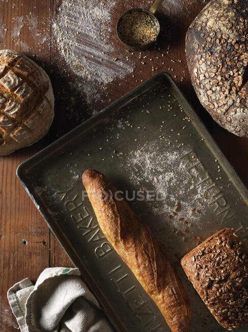 Various bread loaves in tin and on wooden surface — Stock Photo