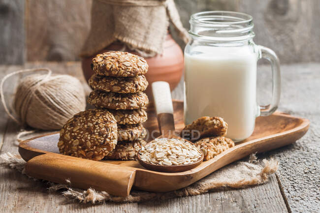 Вівсяне печиво з молоком на підносі на сільському дерев'яному столі — стокове фото