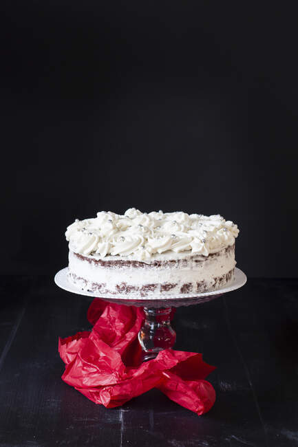 A creamy cake on a cake stand against a black background — Stock Photo