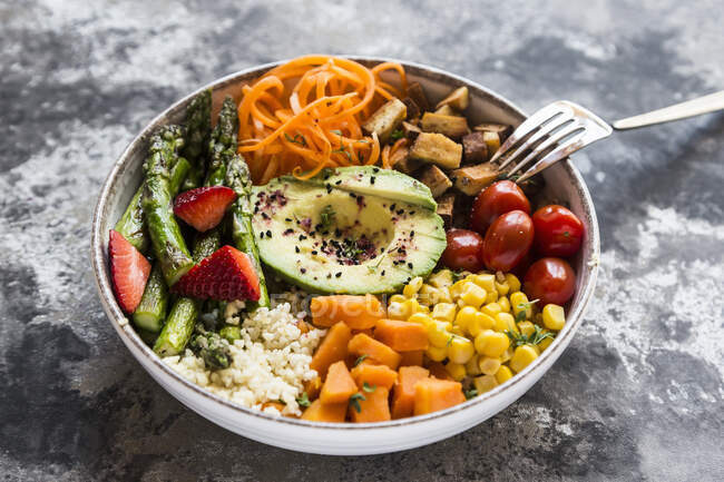 A Buddha bowl with bulgur, green asparagus, strawberries, carrots, tofu, tomatoes, sweetcorn, sweet potatoes and avocado — Stock Photo