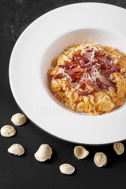 Plate with orecchiette pasta with pumpkin cream and roasted bacon — Stock Photo
