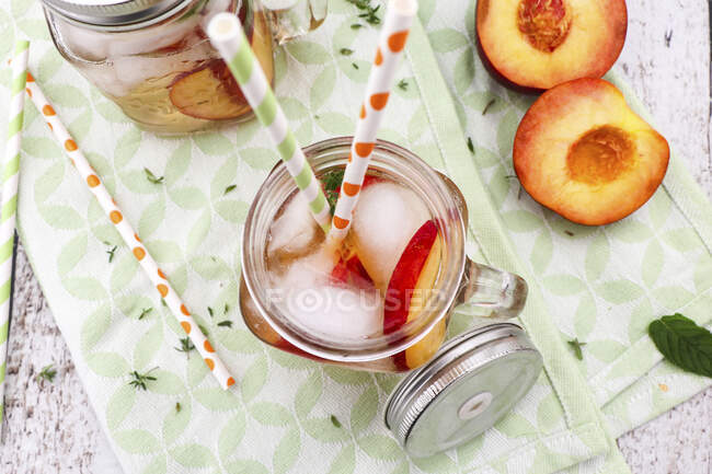 Glass jar with fresh peaches and mint on wooden background — Stock Photo