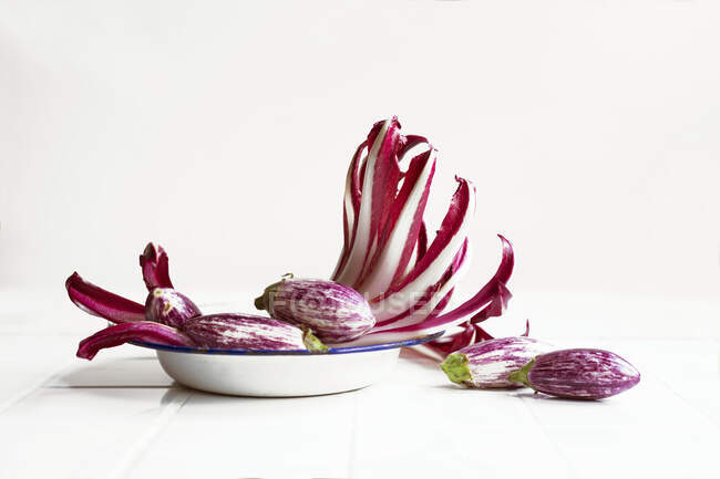 An arrangement of of trevisio and small aubergines on an old enamel plate — Stock Photo