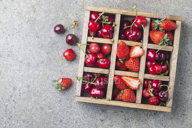Mix of fresh berries in wooden box on rustic background — Stock Photo