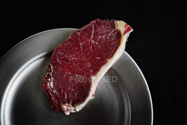 Vieilli steak de boeuf gros plan sur fond noir — Photo de stock