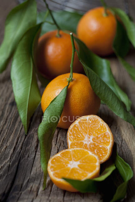 Mandarini con foglie su superficie rustica in legno — Foto stock