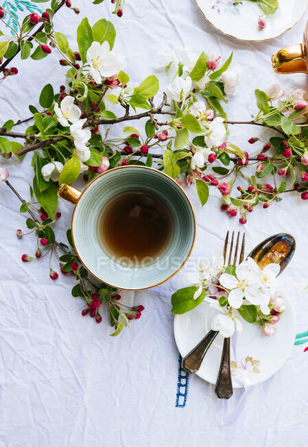 Chávena verde de chá com flor na mesa e talheres — Fotografia de Stock