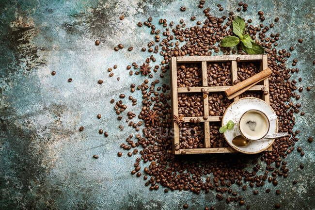 Kaffeebohnen in alter Holzkiste, Tasse frisch zubereiteten Kaffee — Stockfoto