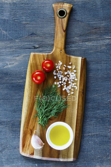 Rural wooden kitchen table with cutting board and ingredients on vintage background — Stock Photo