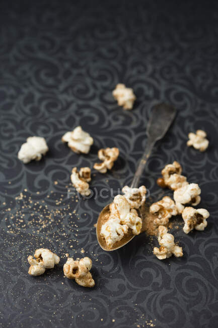 Gilded popcorn on a spoon and a patterned tablecloth — Stock Photo