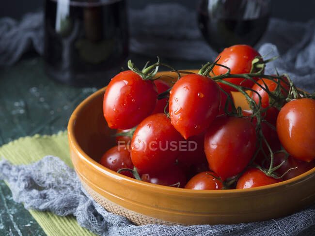 Raw tomatoes in a rustic bowl on dark background — Stock Photo