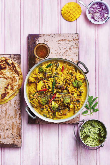 Blumenkohl und Romanesco-Blumenkohl-Curry mit Kichererbsen, Chili, Zwiebeln, serviert mit Reis, Brot, Mango und rohen Zwiebeln — Stockfoto
