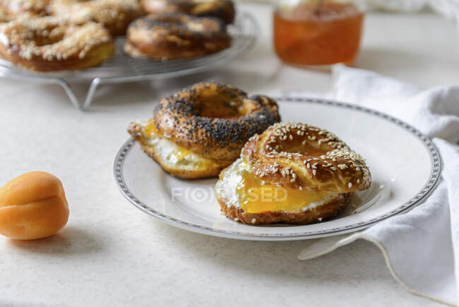 Rosquillas recién horneadas con relleno de mermelada de albaricoque y queso crema en el plato - foto de stock