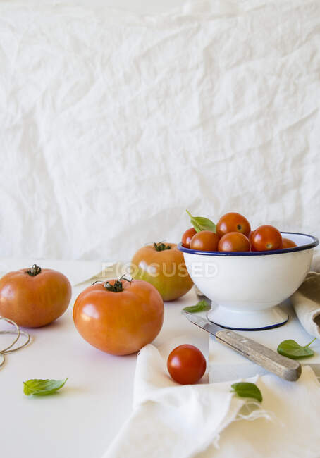 Varios tomates en y al lado de un tazón - foto de stock