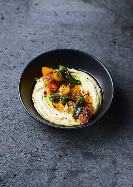 Hummus with chili peppers and tomatoes in bowl — Stock Photo