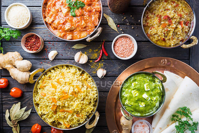 Diverse ciotole con cibo indiano assortito: pollo, riso al curry, lenticchie, paneer, chapati e spezie — Foto stock