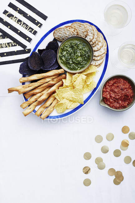 Patatas fritas, galletas y palitos de pan con salsas para Nochevieja - foto de stock