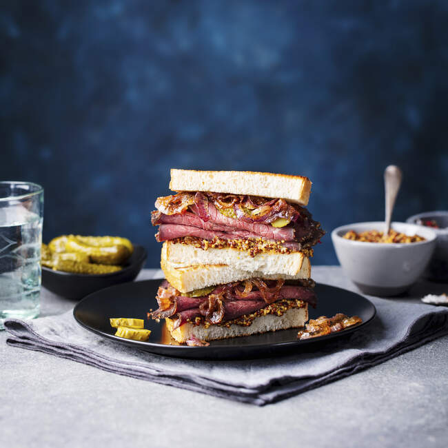 Sandwich de rosbif en un plato con encurtidos - foto de stock