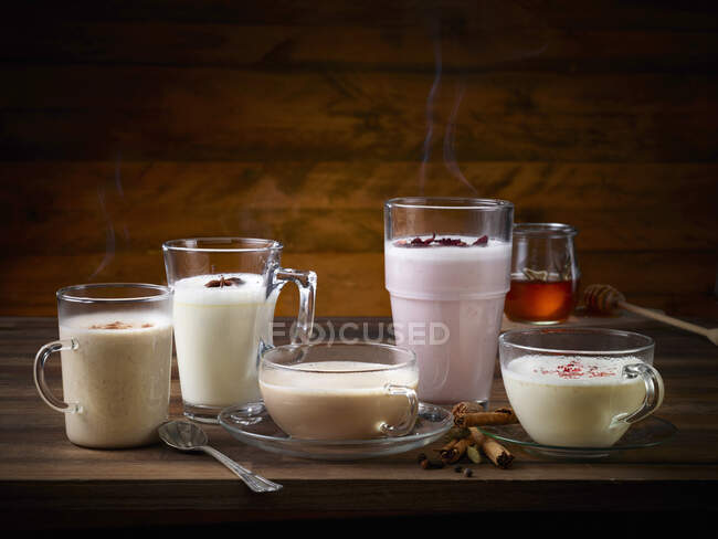 Two glasses of milk with cinnamon and anise on a wooden table — Stock Photo