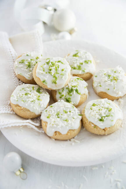 Kekse mit weißer Glasur, Limettenschale und Kokoskrümeln — Stockfoto
