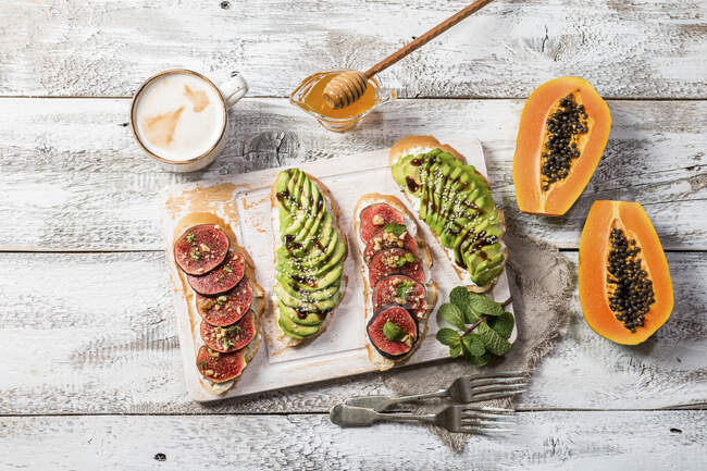 Fatias de pão de pequeno-almoço saudáveis com abacate e figos, xícara de café e mel — Fotografia de Stock