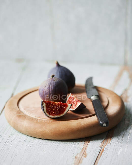 Fresh figs, whole and cut with knife on wooden board — Stock Photo