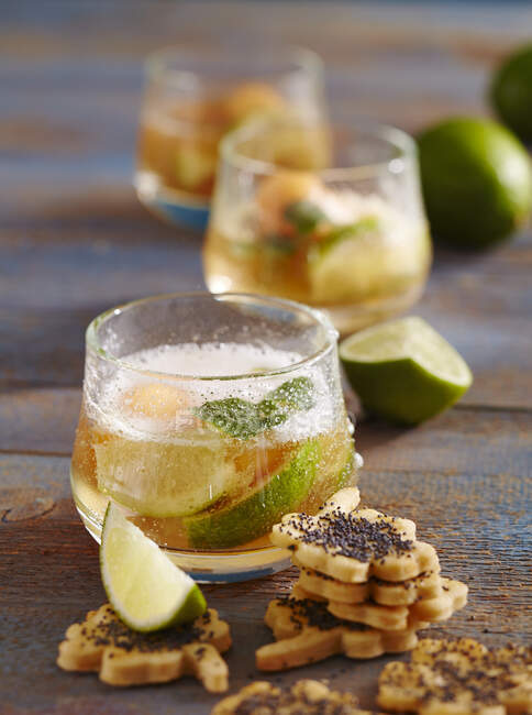 Glasses of caipirinha punch with melon with party biscuits — Stock Photo