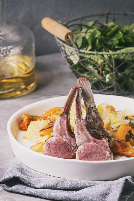 Sous vide sliced rack of lamb with sauce and backed sweet potatoes served in ceramic plate with green salad and white wine — Stock Photo