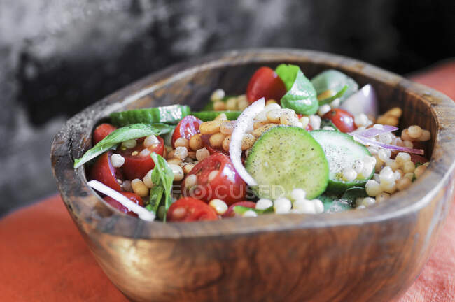 Salada de cuscuz israelense com pepinos, tomates e manjericão fresco em tigela de madeira — Fotografia de Stock