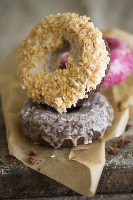 Coconut, chocolate and pomegranate donuts on paper — Stock Photo