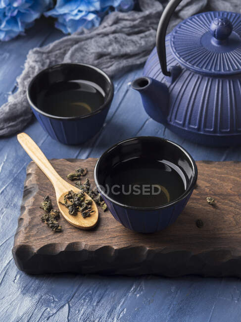 Té verde en tazas azules con maceta de té de hierro fundido azul - foto de stock