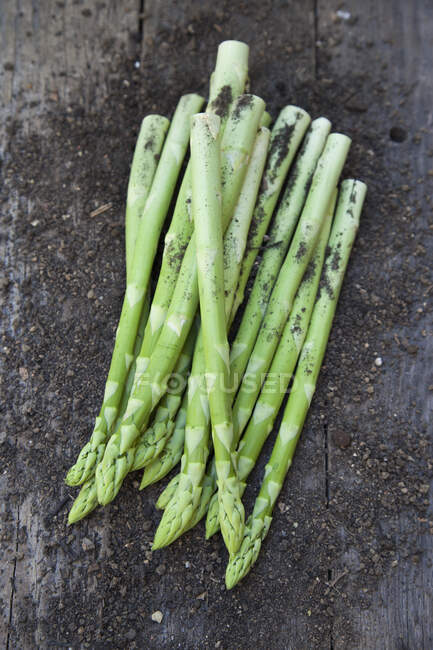 Green asparagus with soil on a wooden background — Stock Photo