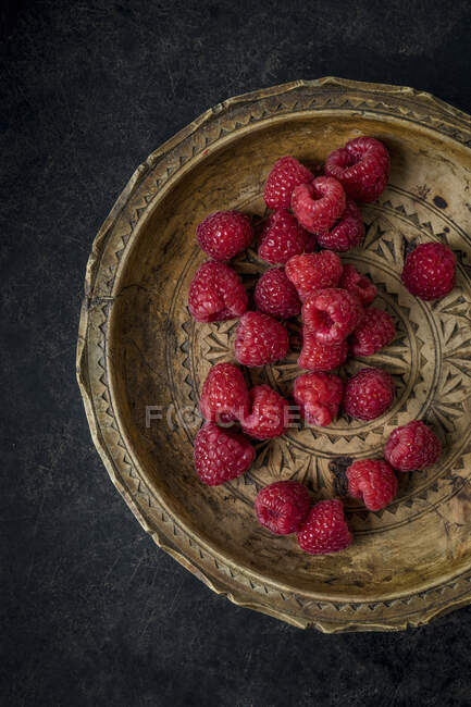 Fresh raspberries on vintage wooden plate — Stock Photo