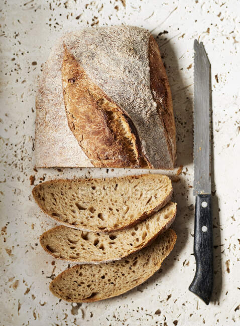 Un pain de levain tranché assis sur une surface de pierre — Photo de stock