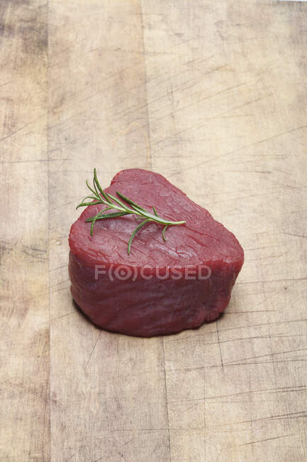 Ein rohes Rinderfilet mit einem Rosmarinzweig — Stockfoto