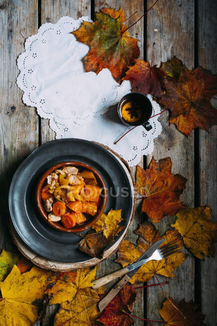 Hühnercurry mit Kürbis, einer Tasse Tee und Herbstblättern — Stockfoto