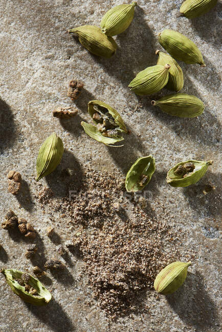 Cardamom pods with ground cardamom on stone from overhead — Stock Photo