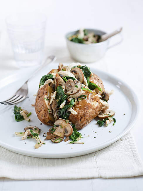 Baked potato with chicken, mushrooms and spinach — Stock Photo