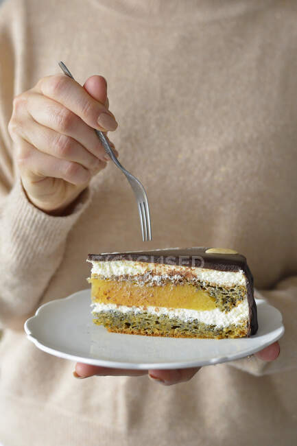 Woman holding a plate with cake, cake with orange jelly and chocolate — Stock Photo