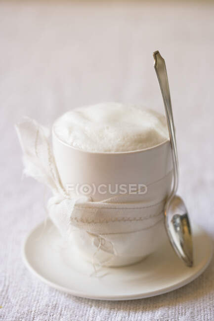 Um cappuccino com um arco e uma colher — Fotografia de Stock