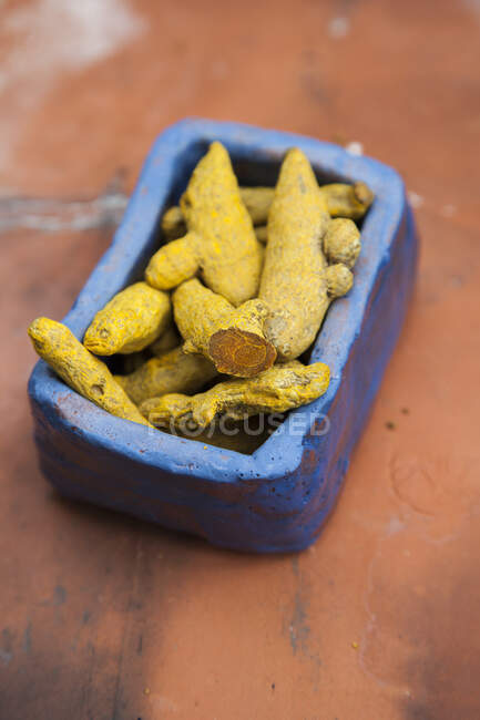 Raízes de açafrão secas em uma tigela de cerâmica azul — Fotografia de Stock