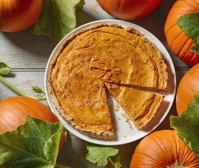 Homemade pumpkin pie with autumn leaves on a wooden background. top view. — Stock Photo