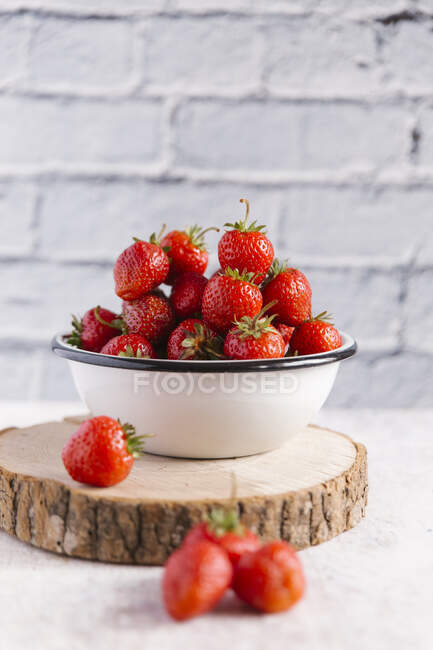 Enamel bowl of fresh strawberries on wooden board — Stock Photo
