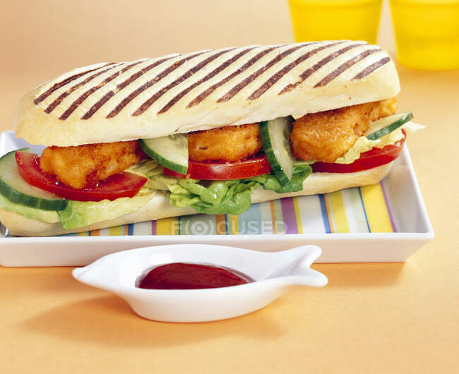 Baguette-Sandwich vom Grill mit gebackenem Fisch, Tomaten, Gurken, Salat und Ketchup — Stockfoto
